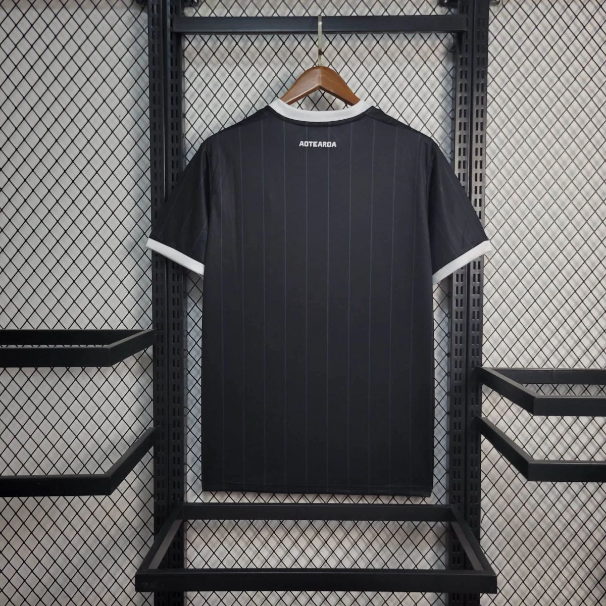 Back view of NEW ZEALAND 2026 HOME jersey displayed on a hanger against a grid backdrop.