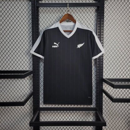 NEW ZEALAND 2026 HOME black jersey displayed on a hanger, featuring Puma logo and white details.
